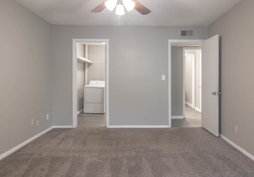 an empty room with a ceiling fan and a closet with a washer and dryer