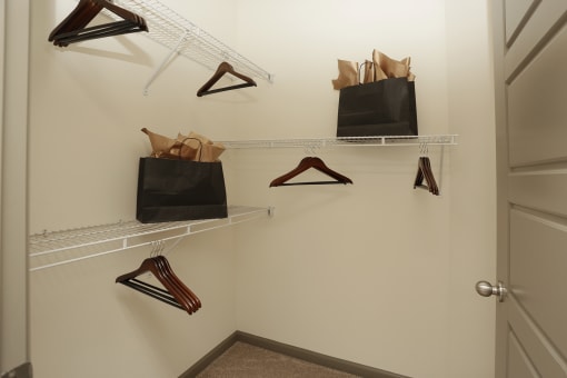 a walk in closet with shoe racks and bags