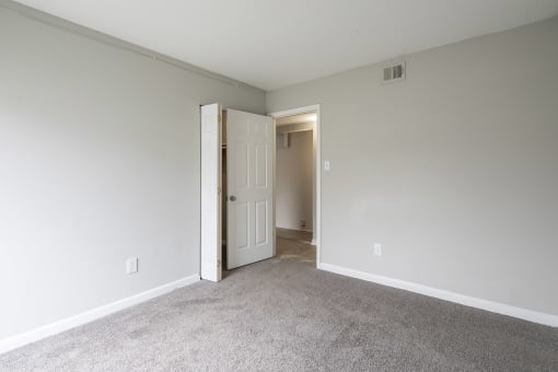 an empty bedroom with a door open to a closet