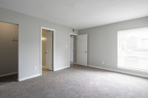 an empty living room with a door to a closet and a window