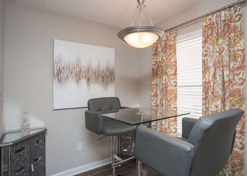 One-Bedroom Apartments in Atlanta, GA - City Park - Dining Area with Glass Table, Chandelier, and Large Window.