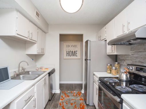 Atlanta, GA Apartments Near Mercedes-Benz Stadium - City Park - Kitchen with Modern Wood-Style Flooring, White Flat-Panel Cabinets, and Stainless-Steel Appliances.