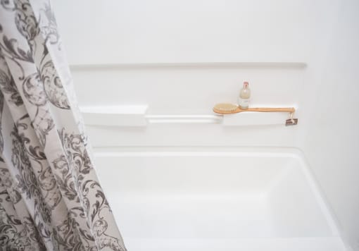 a white bathtub with a shower curtain and a soap dispenser on the shelf