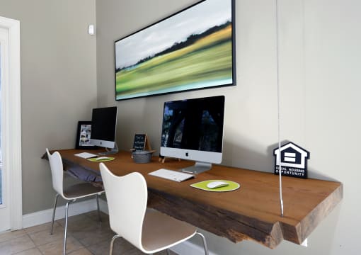 a home office with a desk with two computers and a large monitor on the wall