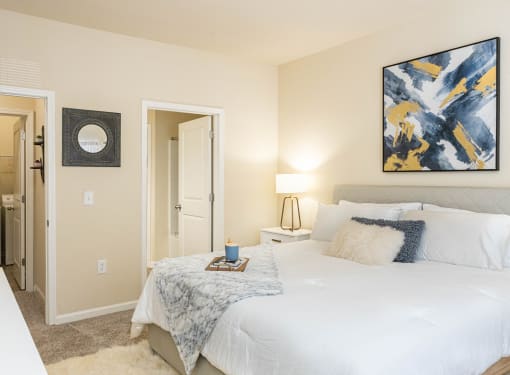 a bedroom with a white bed and a painting on the wall