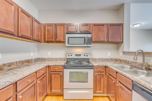 a kitchen with wood cabinets and granite counter tops and a stove and microwave