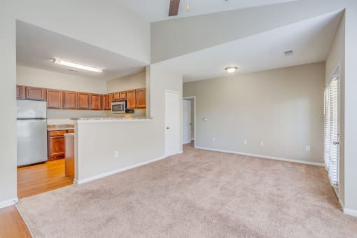 the living room and kitchen of an empty house with a carpeted floor