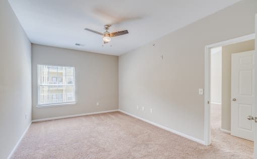 an empty room with a ceiling fan and a window