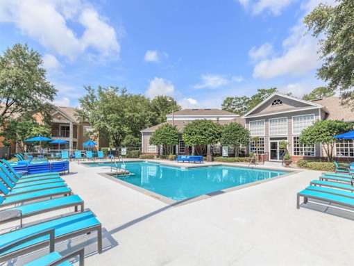 A swimming pool surrounded by blue lounge chairs and umbrellas.