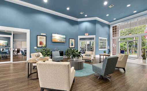 A room with blue walls and wooden floors has a large table surrounded by chairs.