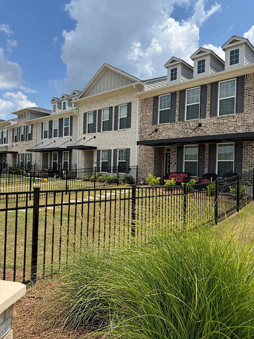 A row of houses with black fences in front.