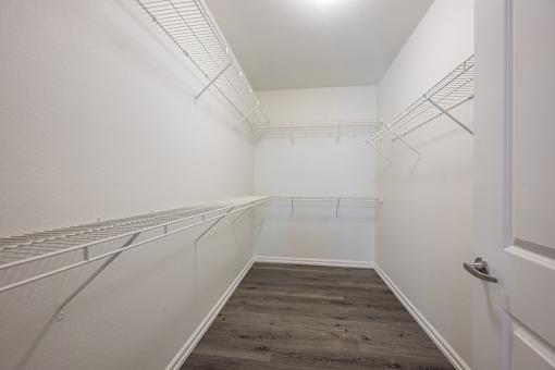 A walk in closet with a white door and shelves.