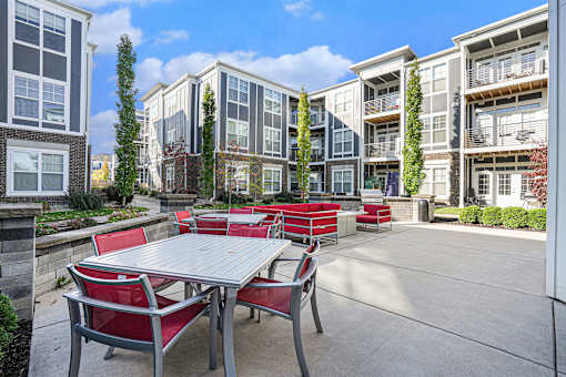 A patio with a table and chairs is surrounded by apartment buildings.