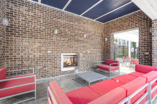 A patio with red couches and a brick wall.