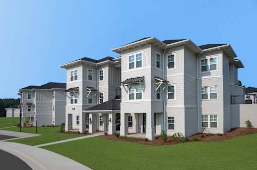 A row of modern houses with white exteriors and dark roofs.