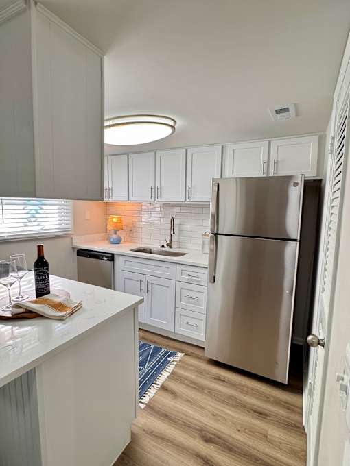 A kitchen with white cabinets and a stainless steel refrigerator.
