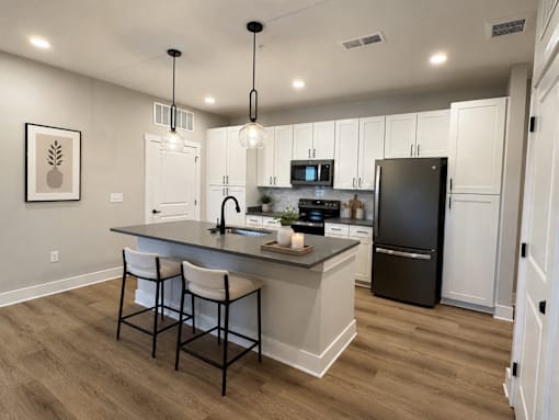 A kitchen with a black refrigerator and white cabinets.