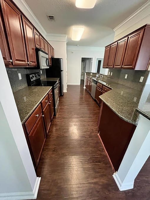 a kitchen with brown cabinets and a wood floor