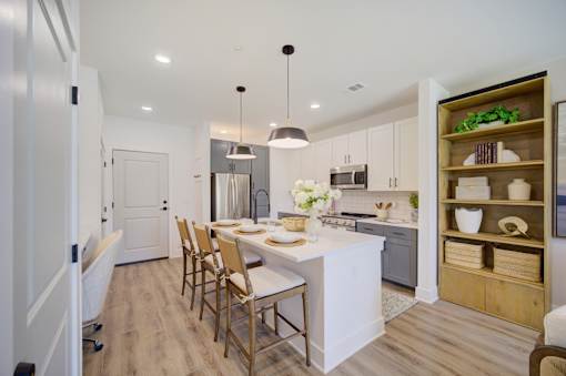 Panama City Beach, FL, Apartments Near Pier Park - Vintage Lake Powell - Kitchen With Large White Island, Bar Seating, Pendant Lights, White And Gray Cabinets, And Stainless Steel Appliances.