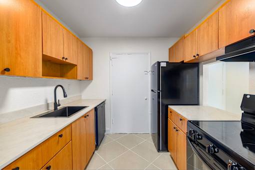 A kitchen with wooden cabinets and black appliances.