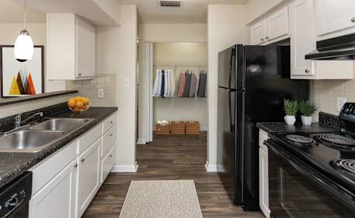 A kitchen with black appliances and white cabinets.