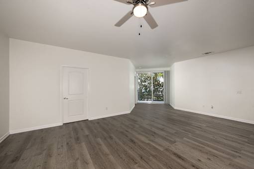 A room with a ceiling fan and wood flooring.