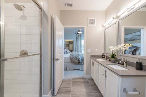 A bathroom with a walk-in shower, double sink vanity, and a large mirror.