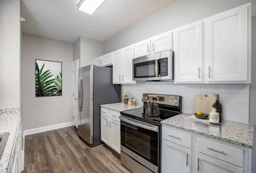 A kitchen with white cabinets and a wooden floor.