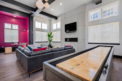 A room with a shiny wooden table and a couch.