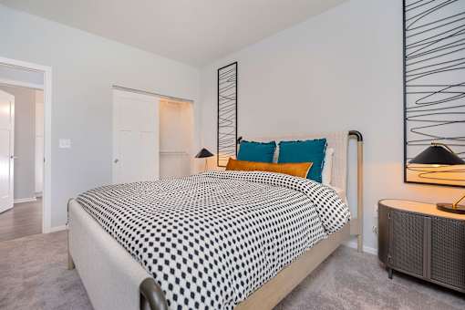 A bedroom with a bed covered in a black and white patterned bedspread.