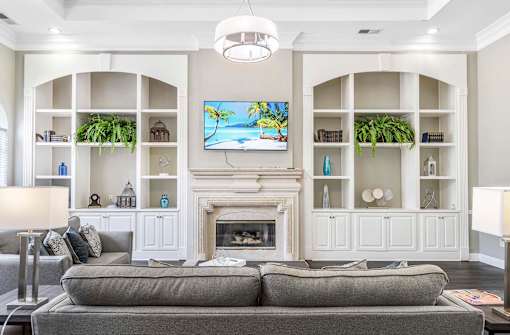 A living room with a grey couch and a fireplace.