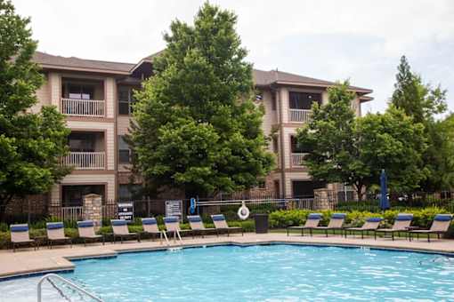 A swimming pool in front of a building surrounded by trees.