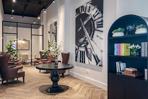 A large clock is on the wall behind a table.