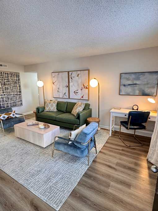 A living room with a green couch, a blue chair, and a wooden coffee table.