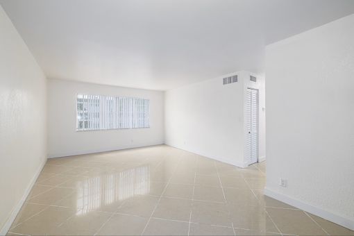 A spacious room with a window and a white door.
