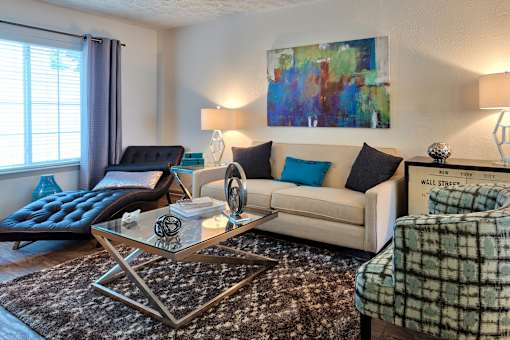 A living room with a couch, a chair, a coffee table, and a painting on the wall.