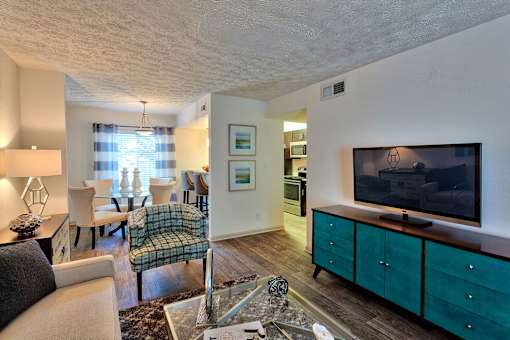 A living room with a couch, chairs, and a television.