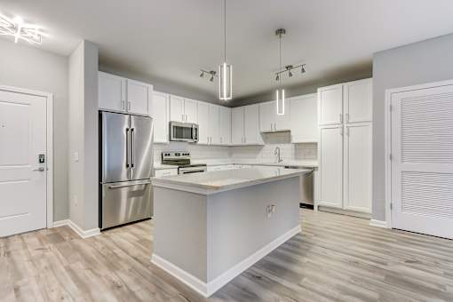 A modern kitchen with a white island and stainless steel appliances.