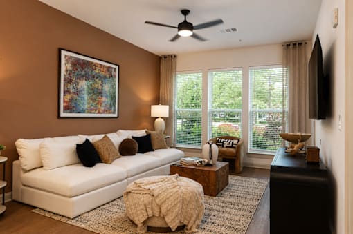 A living room with a white couch and a painting on the wall.