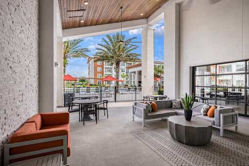 A patio with a table and chairs overlooking a balcony with palm trees.