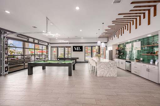 A billiard table is in the middle of a room with a pool table and a foosball table.