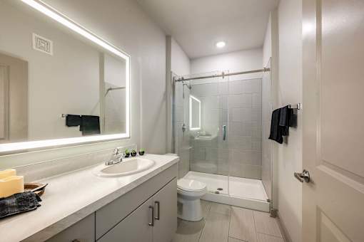 A bathroom with a sink, mirror, and shower.