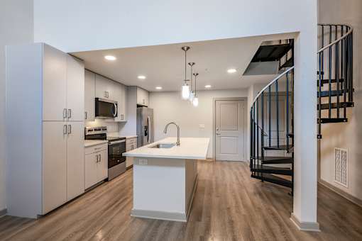 A modern kitchen with a white island and wooden floors.