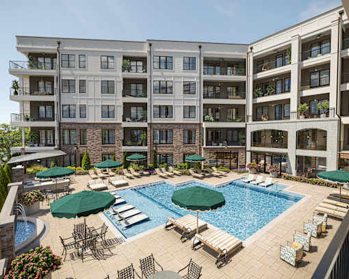 A large swimming pool surrounded by lounge chairs and umbrellas in front of a multi-story apartment building.