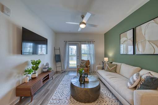 A living room with a white couch, a coffee table, and a ceiling fan.