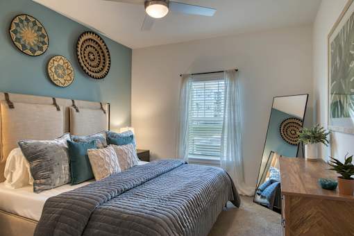 A bedroom with a large bed and a mirror on the dresser.