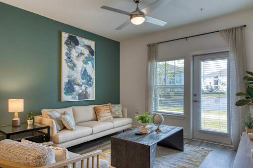 A living room with a couch, a table, a lamp, a plant, and a painting on the wall.