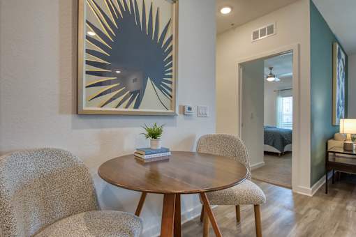 A modern dining room with a round wooden table and two chairs.