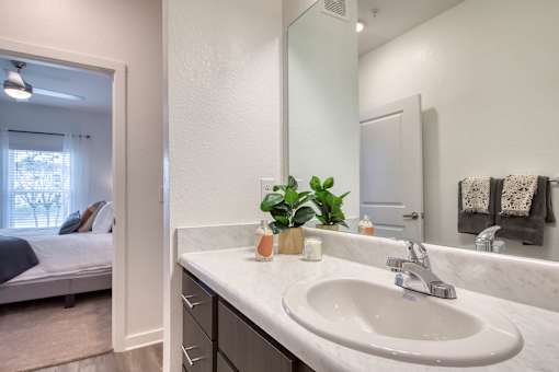 A bathroom with a marble countertop and a large mirror.