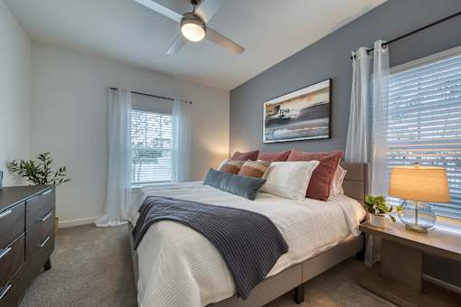 A bedroom with a bed, nightstand, and a ceiling fan.